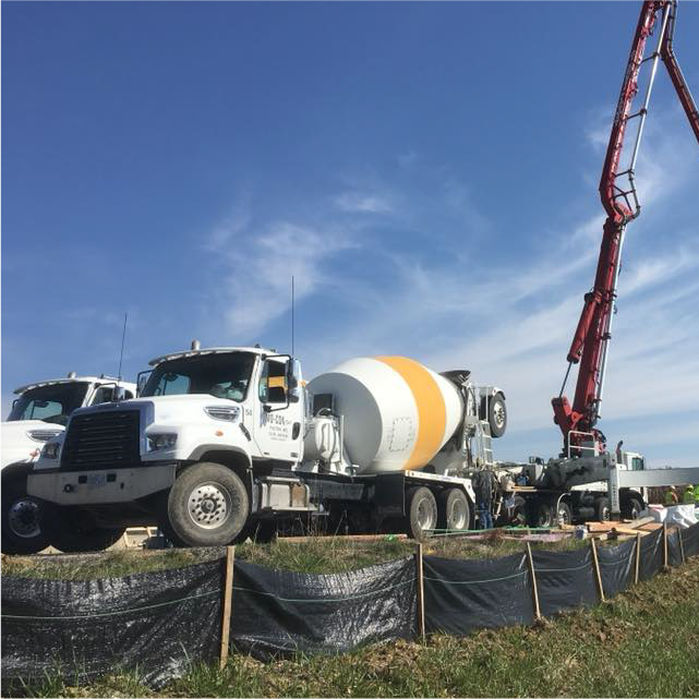 pair of MoCon of Fulton inc cement mixing trucks with cement pumping truck at worksite